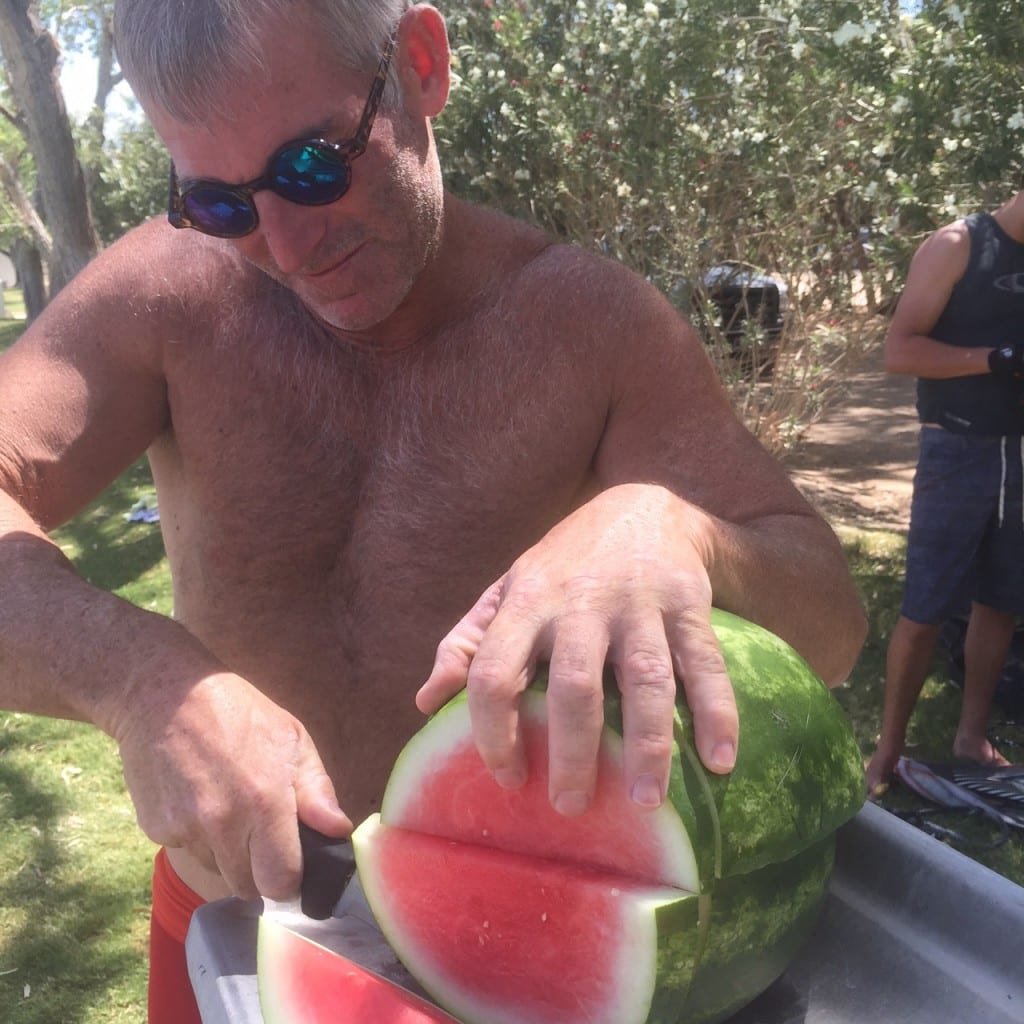 Matthew preparing the cold, ripe, fragrant, watermelon with sea salt sprinkles for water ski tournament guests.