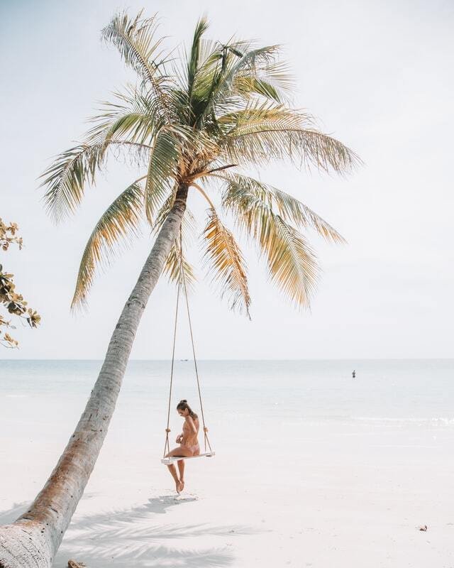 woman sitting in a swing on a beach